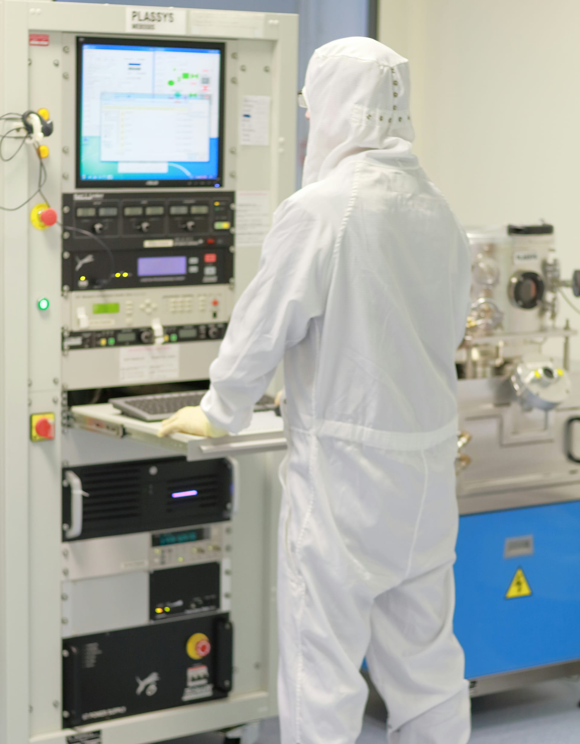 Operator in cleanroompak bedient een machine via het beeldscherm