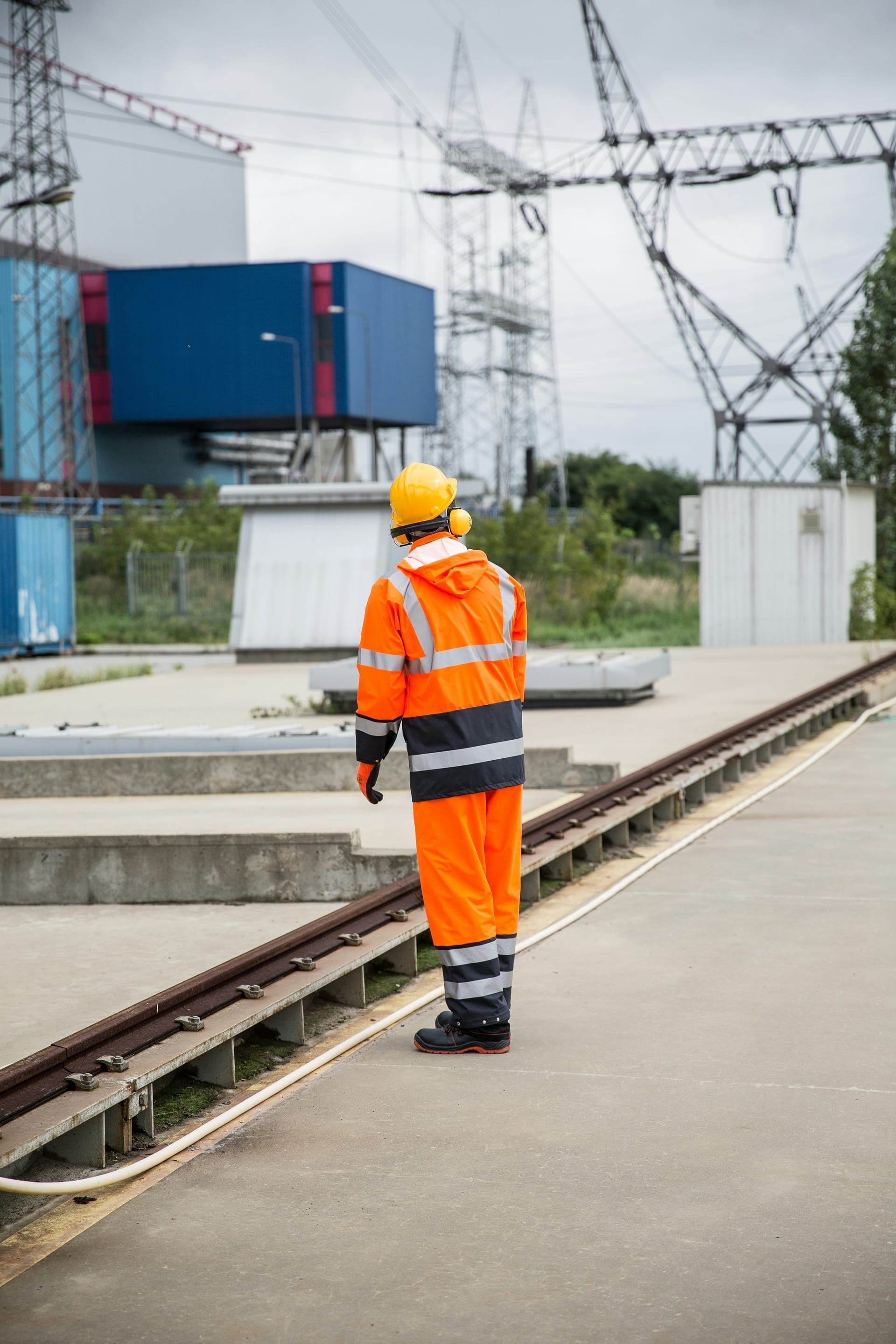 Medewerker in oranje werkkleding op het terrein van een energiecentrale