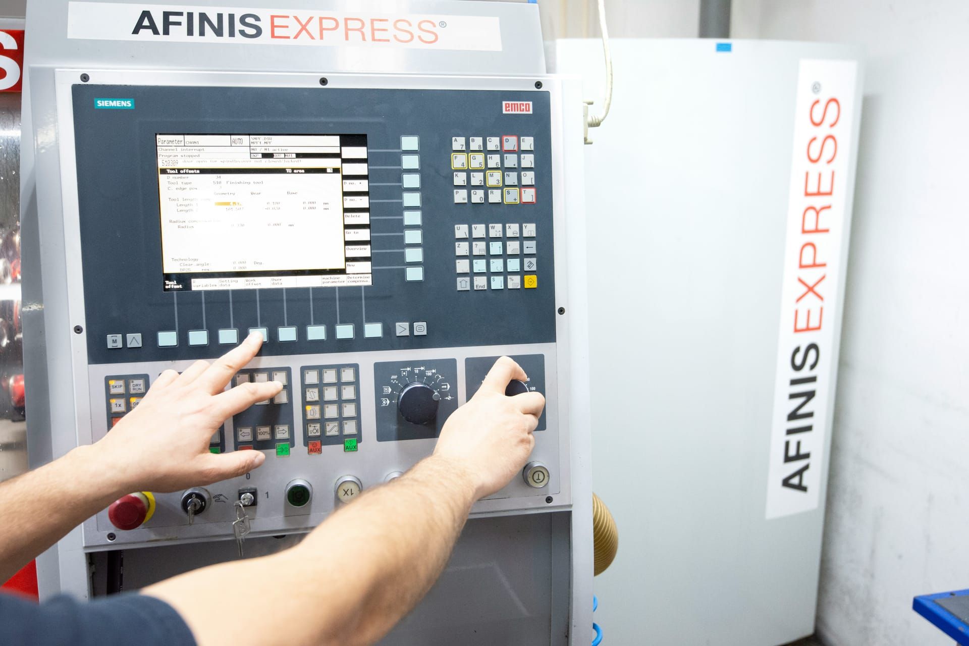 Handen bedienen het bedieningspaneel van een machine op de werkvloer