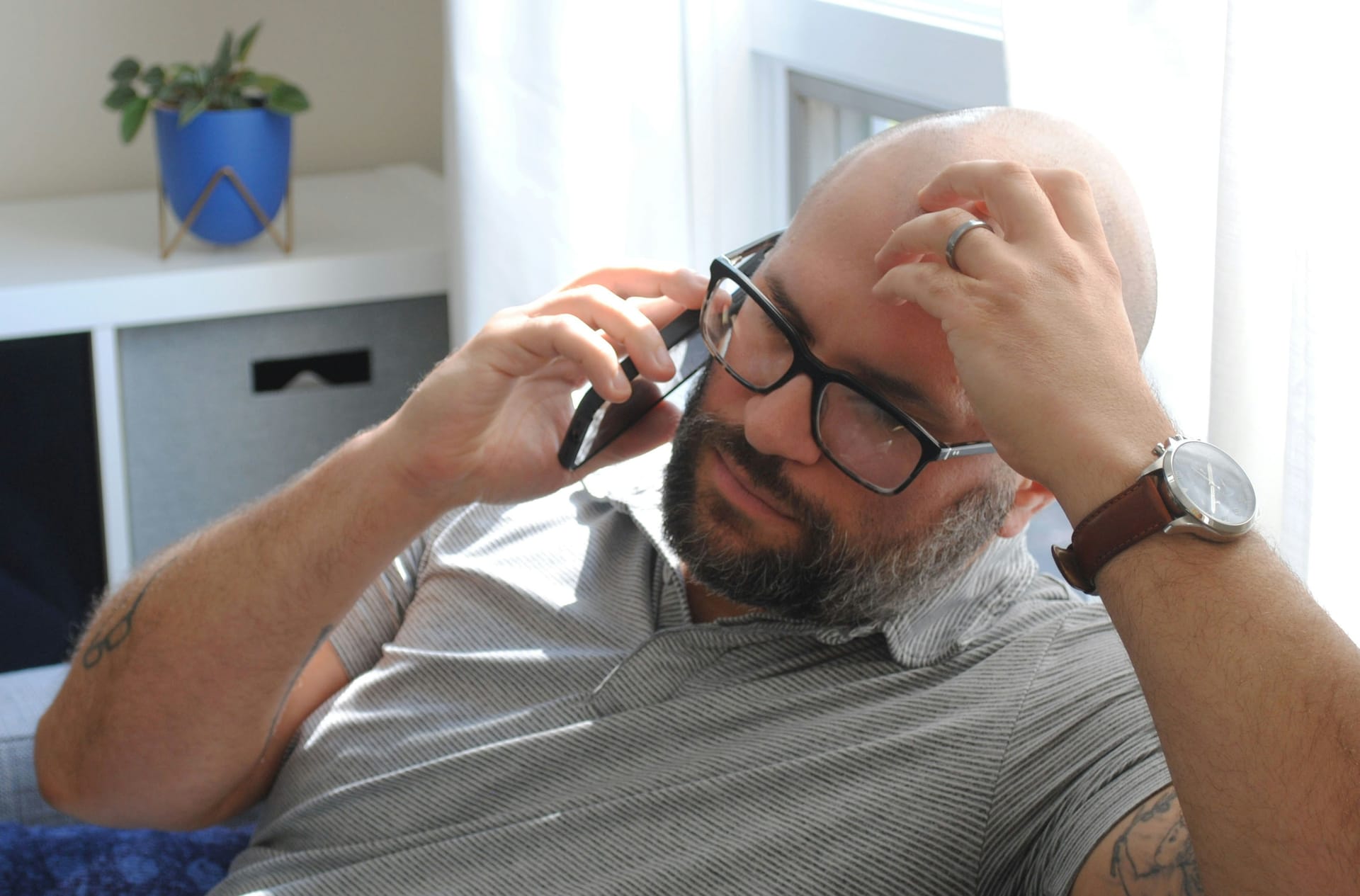 Man met bril voert een telefoongesprek met de hand tegen het hoofd
